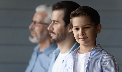 Drei Männer verschiedener Generationen nebeneinander stehend, der jüngste Mann schaut in die Kamera.